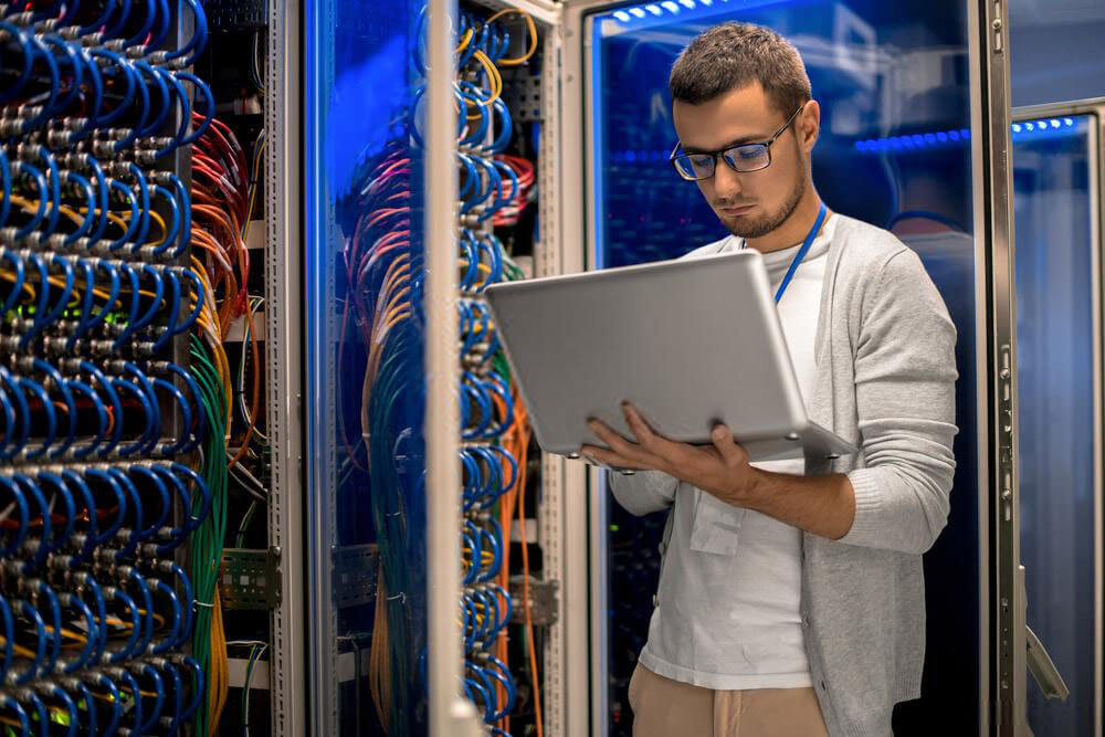 guy with laptop beside supercomputer