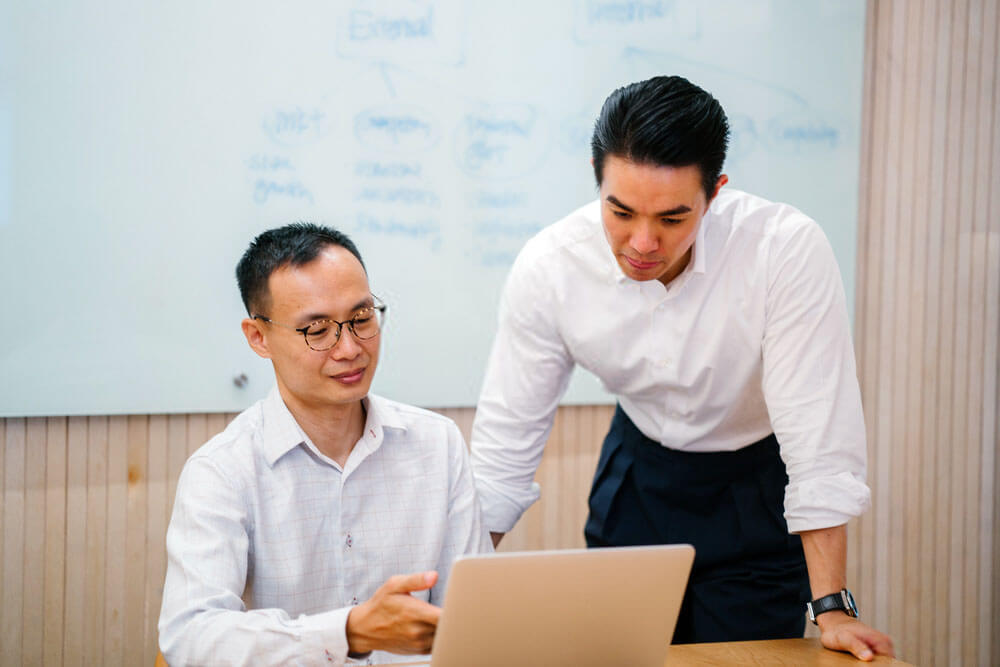 two guys discuss focusing on laptop screen