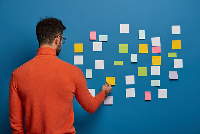 male worker putting his sticky note idea on the wall